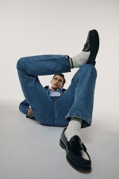 a man sitting on the ground with his legs crossed and feet up in the air