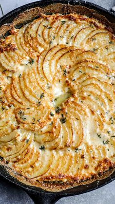 a baked dish in a cast iron skillet topped with potatoes and herbs, ready to be eaten