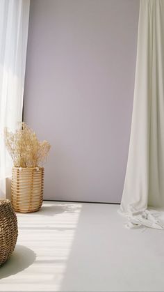 an empty room with white curtains and wicker baskets