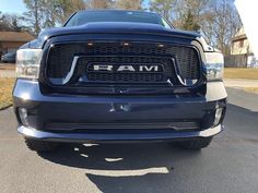 the front end of a blue ram truck parked in a parking lot next to a house