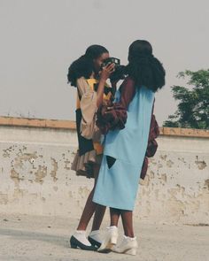 two women standing next to each other taking pictures