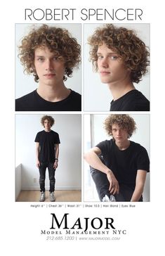 a man with curly hair wearing black shirt and jeans, standing in front of a white wall