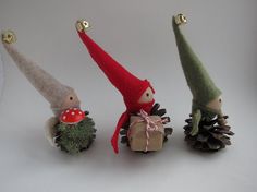 three small gnomes are holding pine cones and one has a mushroom on its back