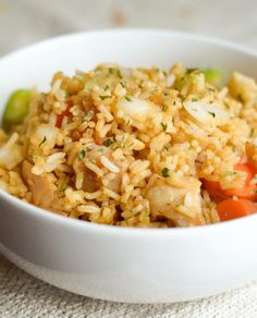 a white bowl filled with rice and veggies on top of a table cloth