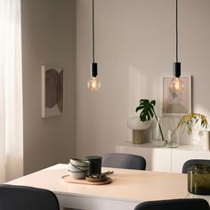 a dining room table with plates on it and two hanging lights above the table in front of them