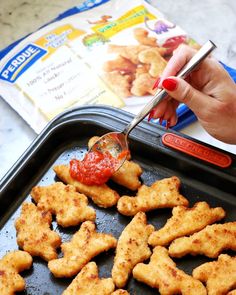 someone is dipping sauce on some chicken nuggies in a pan with a spoon