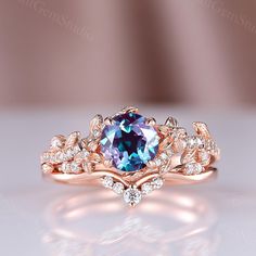 an engagement ring with a blue stone surrounded by white and rose gold leaves on the side