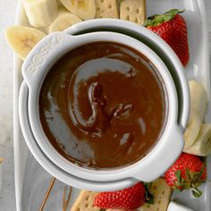 a plate with crackers, strawberries and chocolate dip