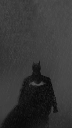 a man in a batman costume walking through the rain with his cape up and cat mask on