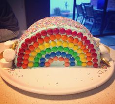 a rainbow cake with white frosting and sprinkles