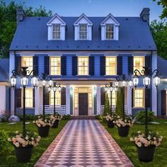 an image of a house at night with lights on and flowers in the front yard