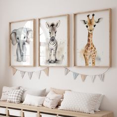 three framed pictures hang on the wall above a wooden bench with pillows and blankets underneath them