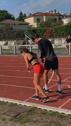 two people standing on a tennis court, one in red shorts and the other in black