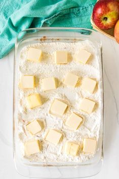 a pan filled with butter and cubed cheese next to apples on a white counter