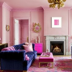 a living room with pink walls and blue couches in front of a fire place