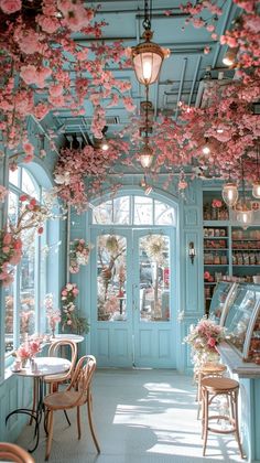 the inside of a restaurant with tables, chairs and flowers hanging from the ceiling above them