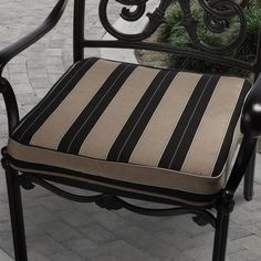 a black and tan striped chair sitting on top of a brick patio next to a potted plant