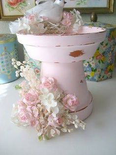 a pink vase filled with flowers on top of a white table next to a mirror