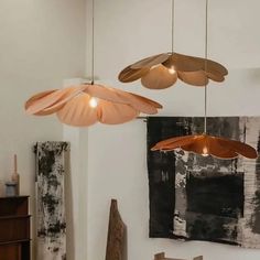 three lights hanging from the ceiling in a room with paintings on the wall and wooden furniture