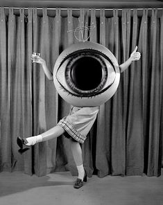 a woman is posing in front of a curtain with an eyeball on her head