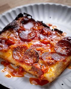 a piece of pizza sitting on top of a white plate covered in ketchup