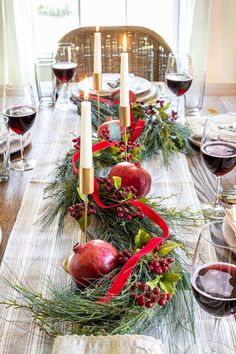 the table is set with candles, fruit and greenery for an elegant holiday centerpiece