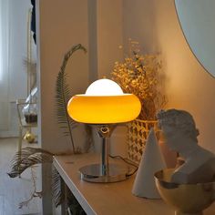 a lamp that is sitting on top of a table next to a bowl and potted plant