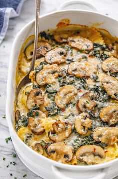 a casserole dish with mushrooms and spinach in it on a white table