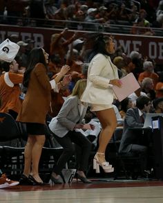 a woman in high heels standing next to a man on the sidelines at a basketball game