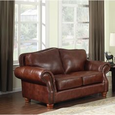 a brown leather couch sitting on top of a rug in front of a large window