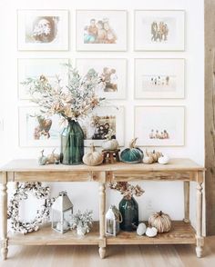 a wooden table topped with lots of vases filled with flowers next to pictures on the wall