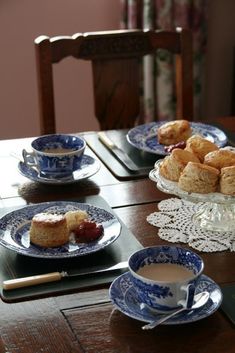 two plates with pastries on them sitting on a table next to cups and saucers