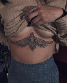 a woman's stomach with a bird tattoo on her belly and the bottom part of her stomach