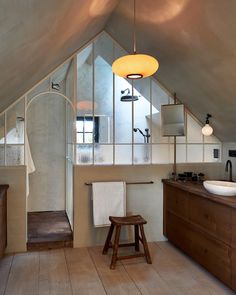 an attic bathroom with wooden floors and white walls