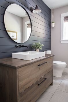 a white sink sitting on top of a wooden dresser next to a toilet in a bathroom