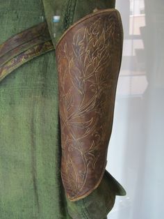 the back of a man's green shirt with brown leather accents