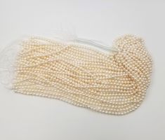 three strands of white pearls are shown on a white surface with one strand in the middle