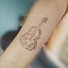 a small guitar tattoo on the arm