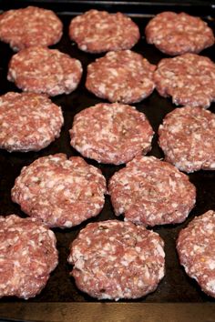 several hamburger patties are on a baking tray ready to be cooked in the oven