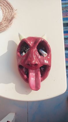 a red mask with horns sticking out of it's mouth sitting on a table