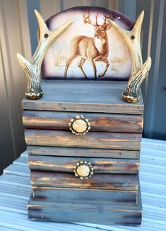 a wooden box with two deer antlers on it's sides and an image in the background