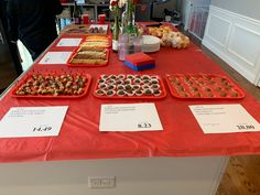 there are many trays of food on the table and one is red with white lettering