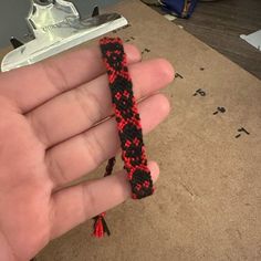 a hand holding a red and black bracelet