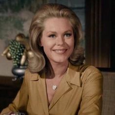 a woman sitting at a table smiling for the camera