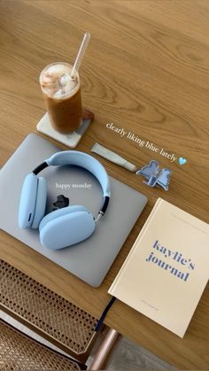 there is a book and headphones on top of the table with a drink next to it