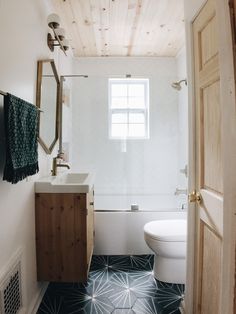 a bathroom with black and white tile flooring and wood accents on the walls, along with a wooden door