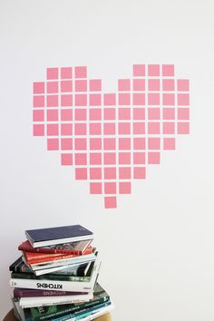 a stack of books sitting on top of a table next to a heart shaped wall decal