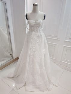 a white wedding dress on display in front of a mirror