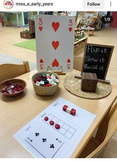 a wooden table topped with cards and dices next to a bowl of candy on top of a table