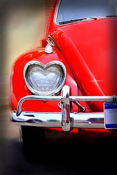 the front end of an old red car with a heart on it's grill